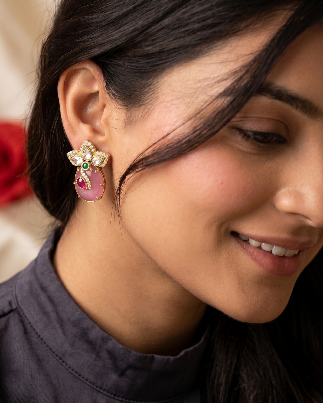 Close-up of a woman wearing a decorative earring with pink gemstones.