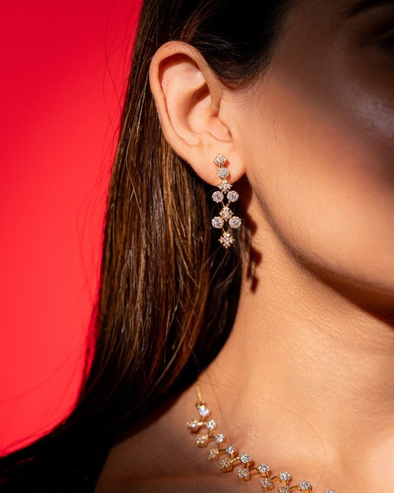 Close-up of a woman wearing a diamond earring with a red background