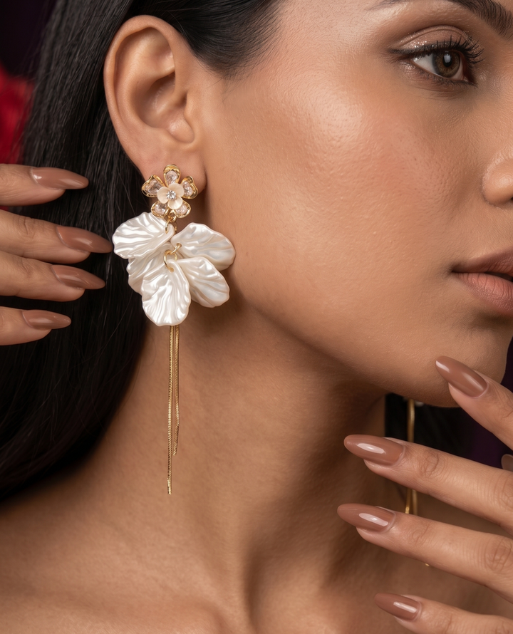 Close-up of a woman wearing a floral earring with gold accents.