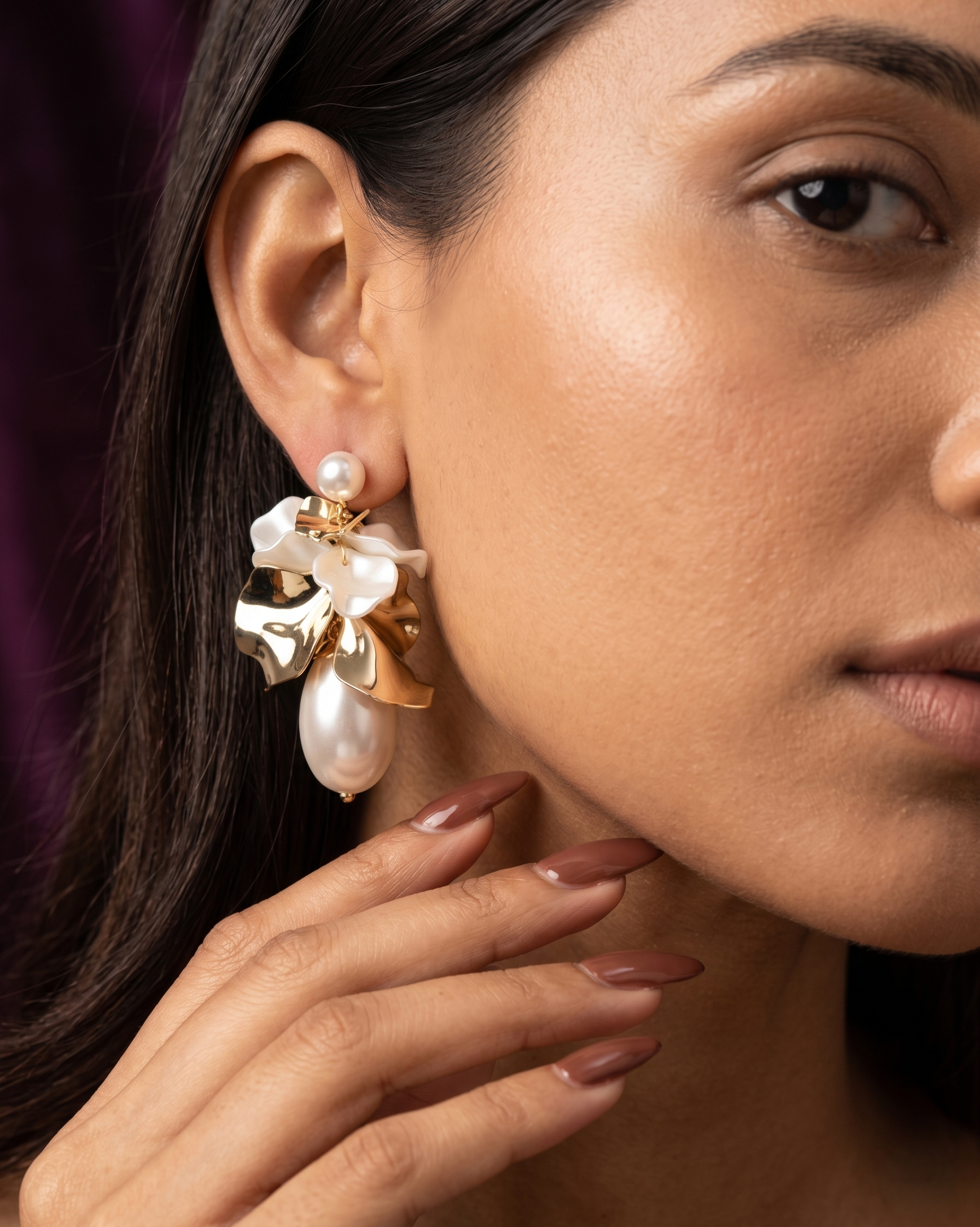 Close-up of a woman wearing a floral earring with pearl-like stones.