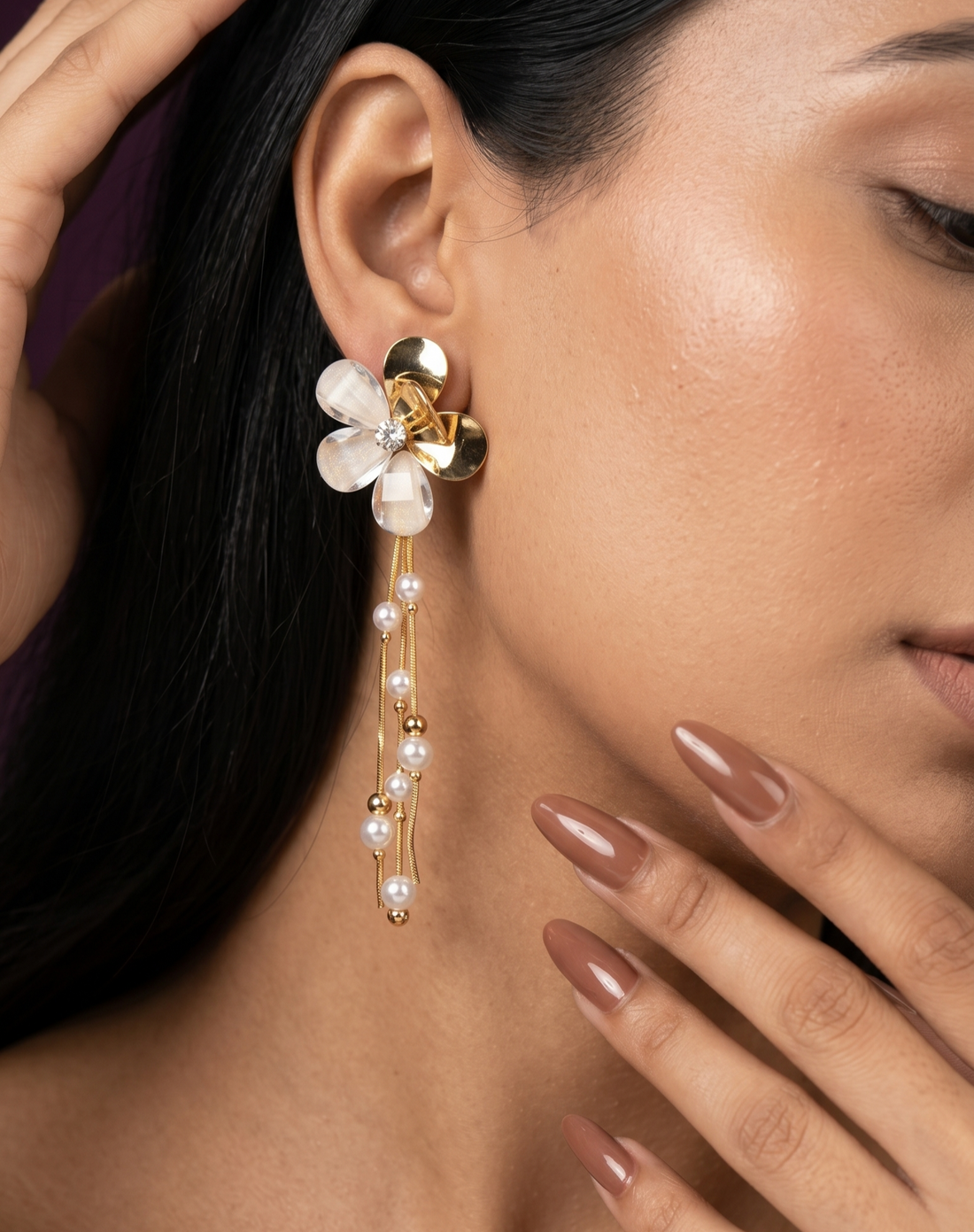 Close-up of a woman wearing a floral earring with pearl details.