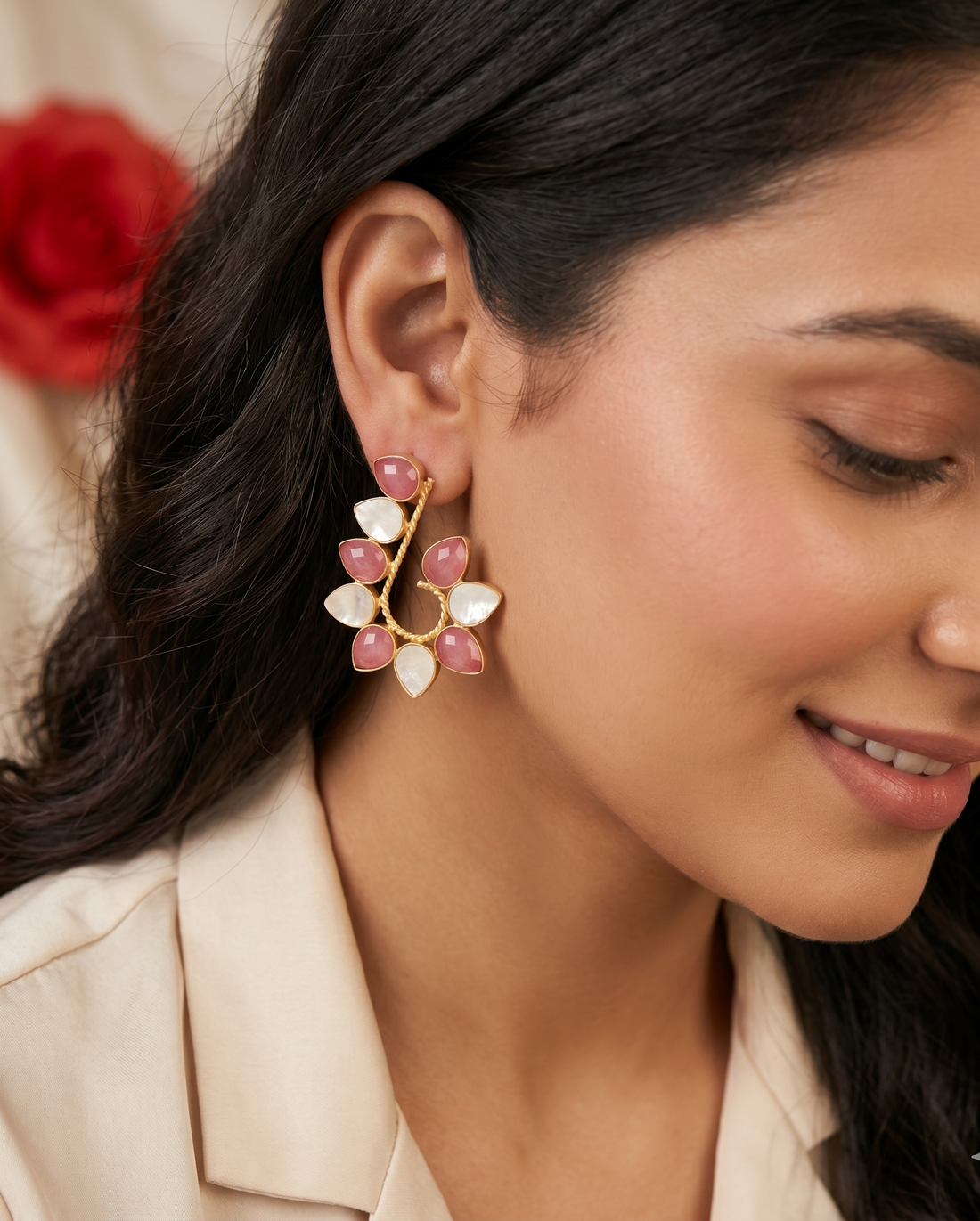 Close-up of a woman wearing a floral earring with pink and white stones.