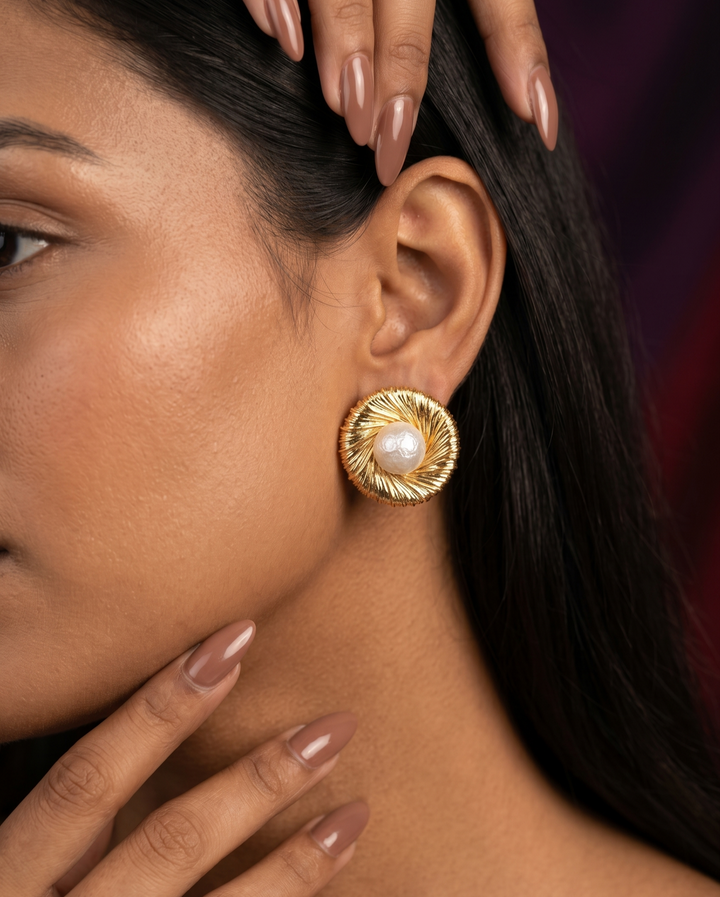 Close-up of a woman wearing a gold earring with a pearl center.