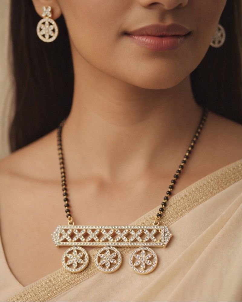 Close-up of a woman wearing a gold necklace and earrings.