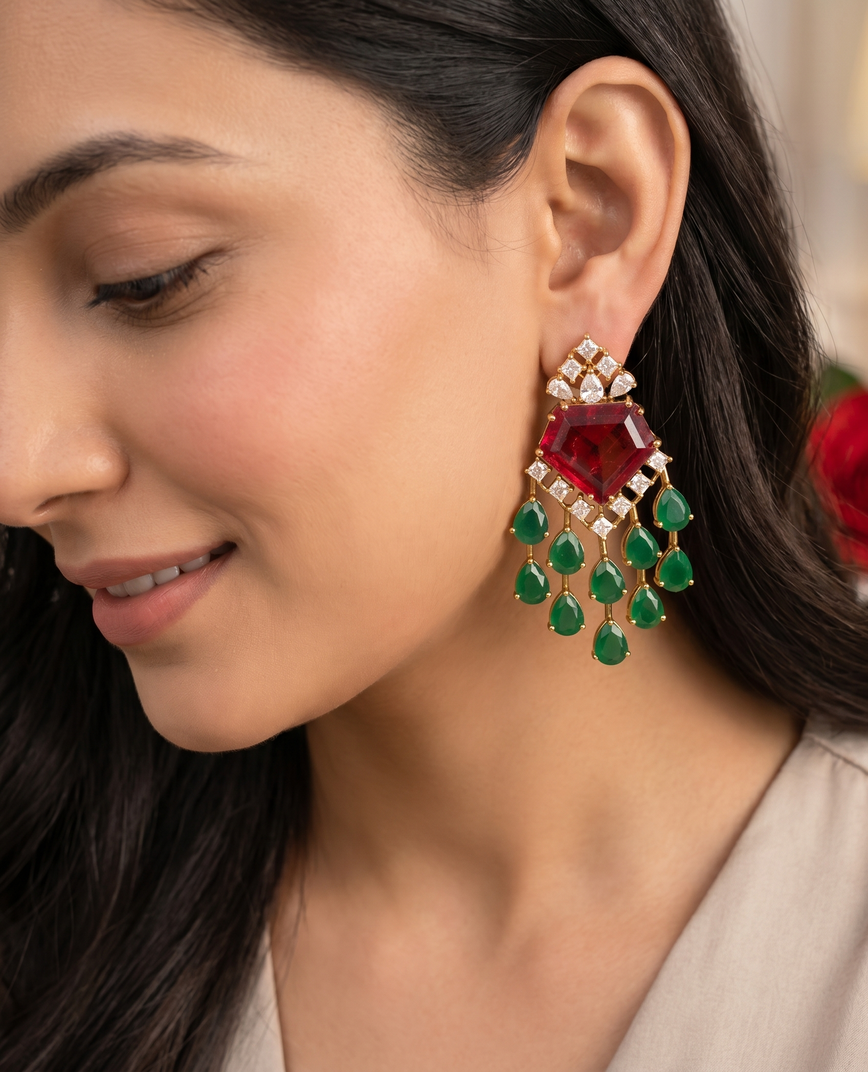 Close-up of a woman wearing a red gemstone earring with green teardrop drops.
