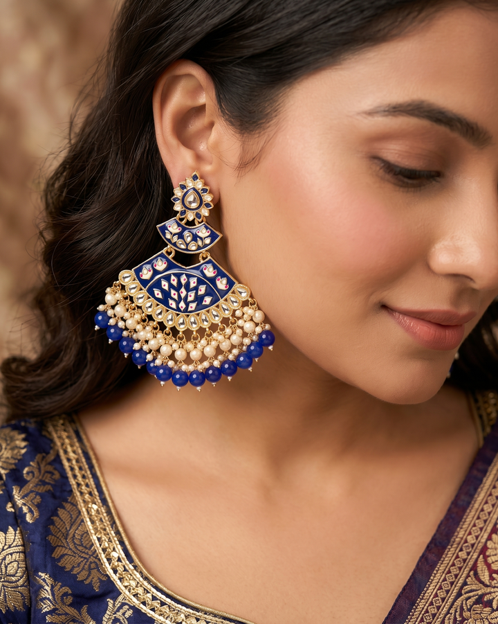 Close-up of a woman wearing blue and gold earrings with a blurred background