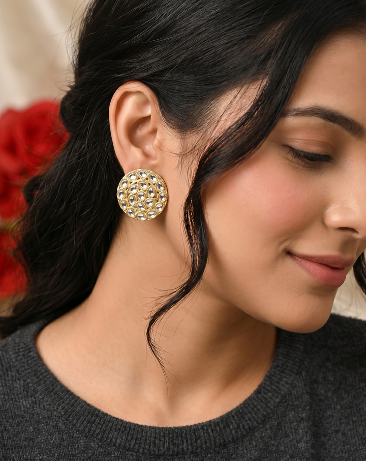 Close-up of a woman wearing gold earrings with a blurred red flower background