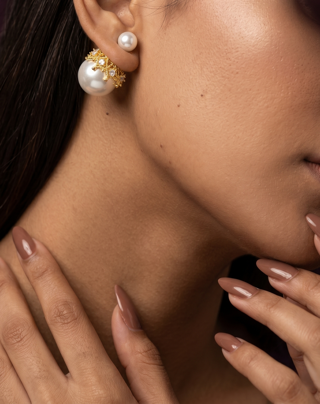 Close-up of a woman wearing pearl earrings with a neutral background