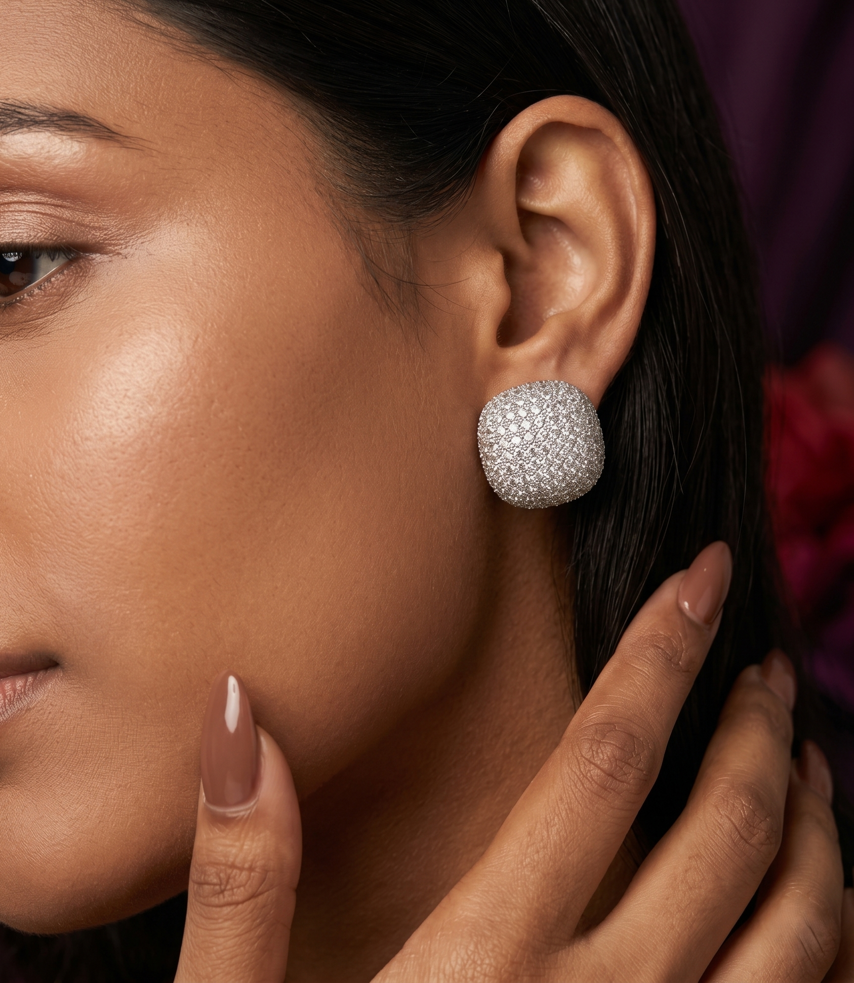 Close-up of a woman wearing silver earrings with a blurred background