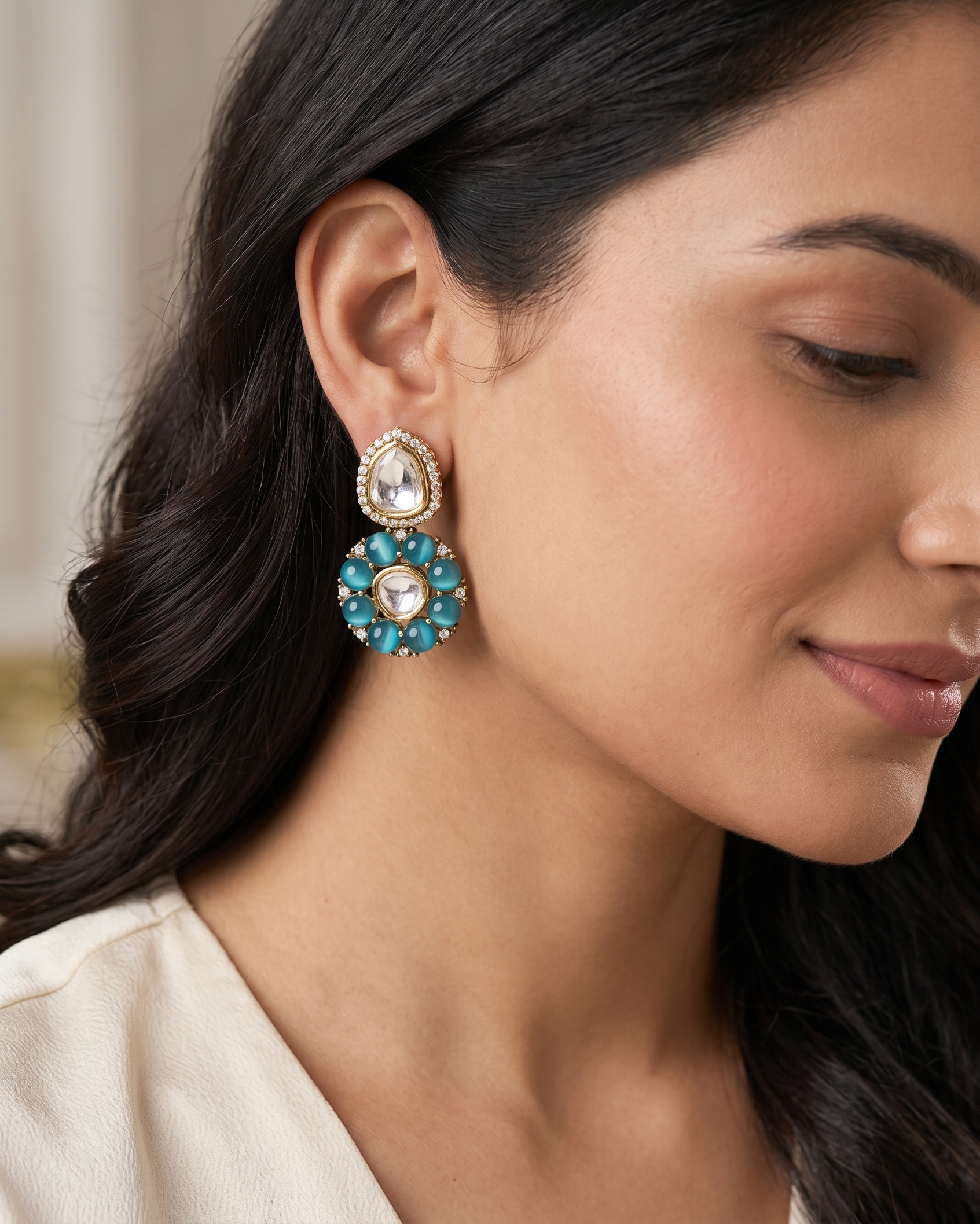 Close-up of a woman wearing turquoise earrings with a neutral background