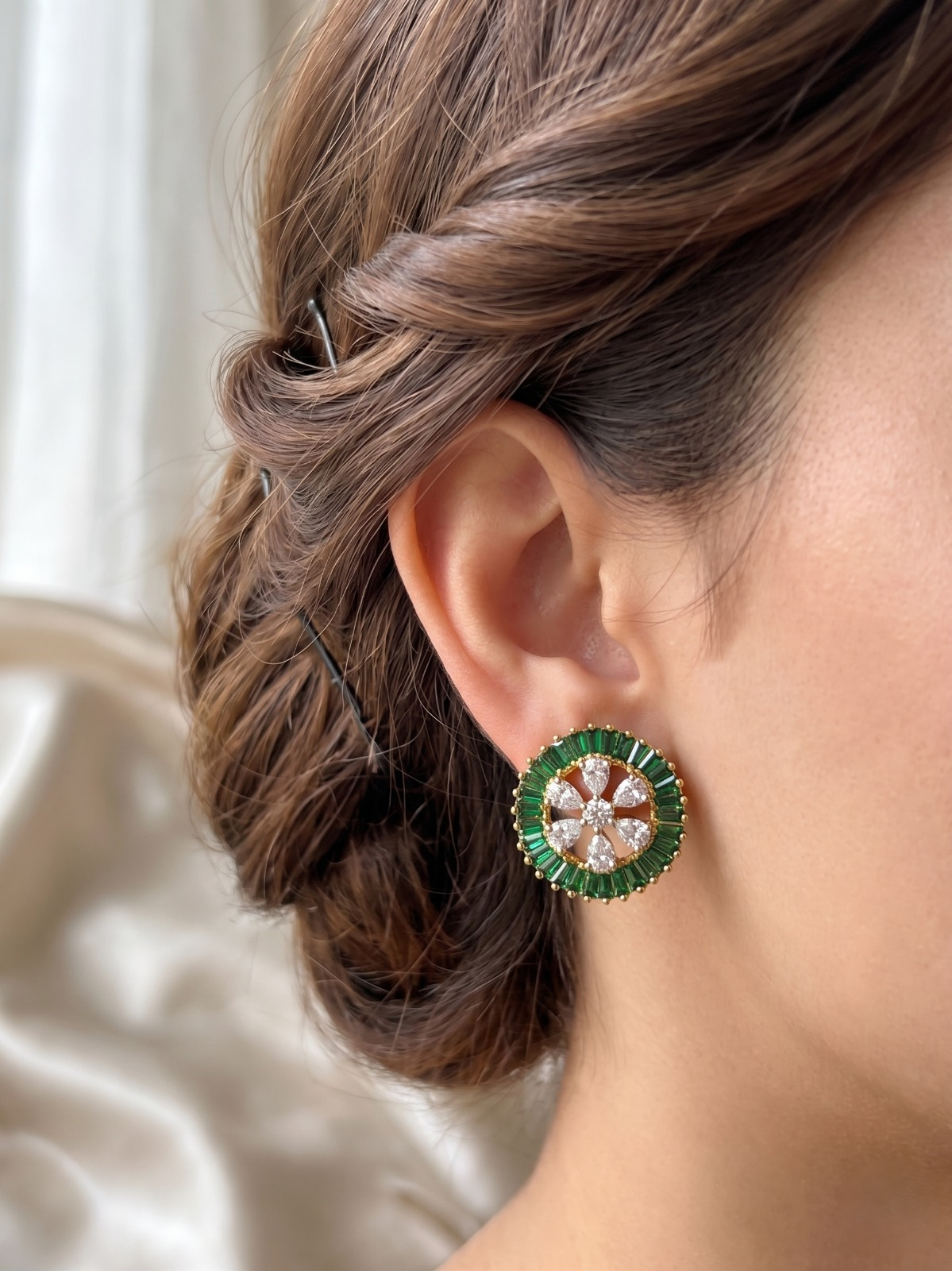 Close-up of an ear wearing a green and clear earring with a blurred background