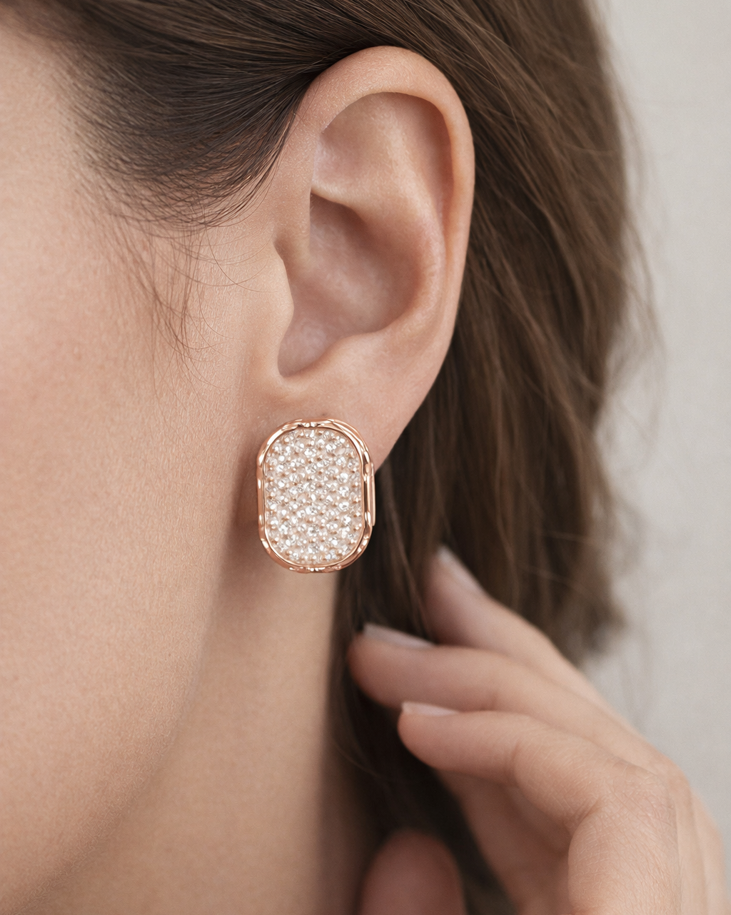 Close-up of an ear wearing a rose gold earring with a textured design.