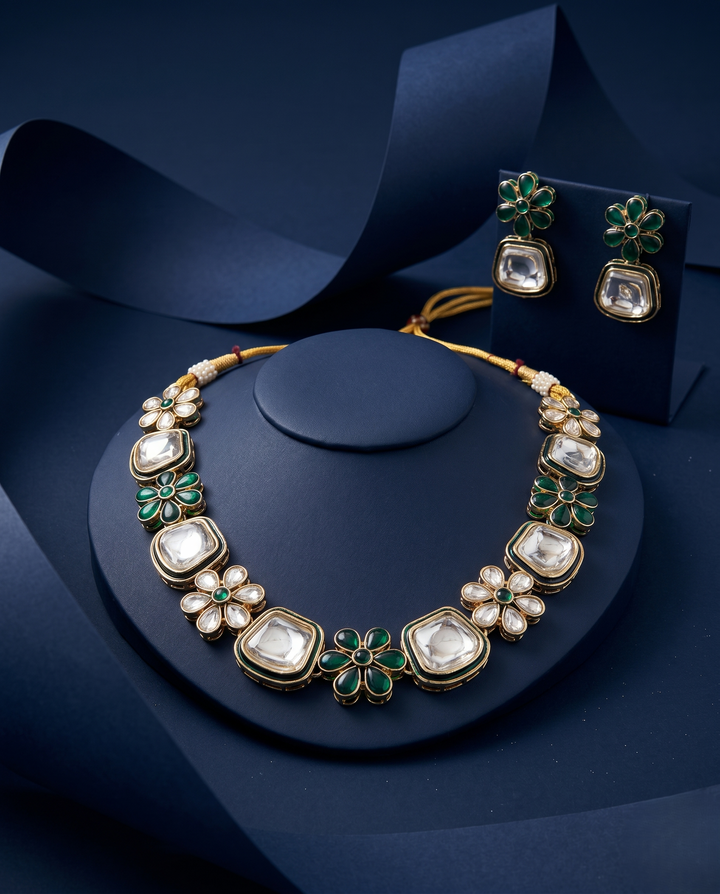 Close up view of polki kundan floral necklace with green enamel paired with matching earrings in gold finish with blue background 
