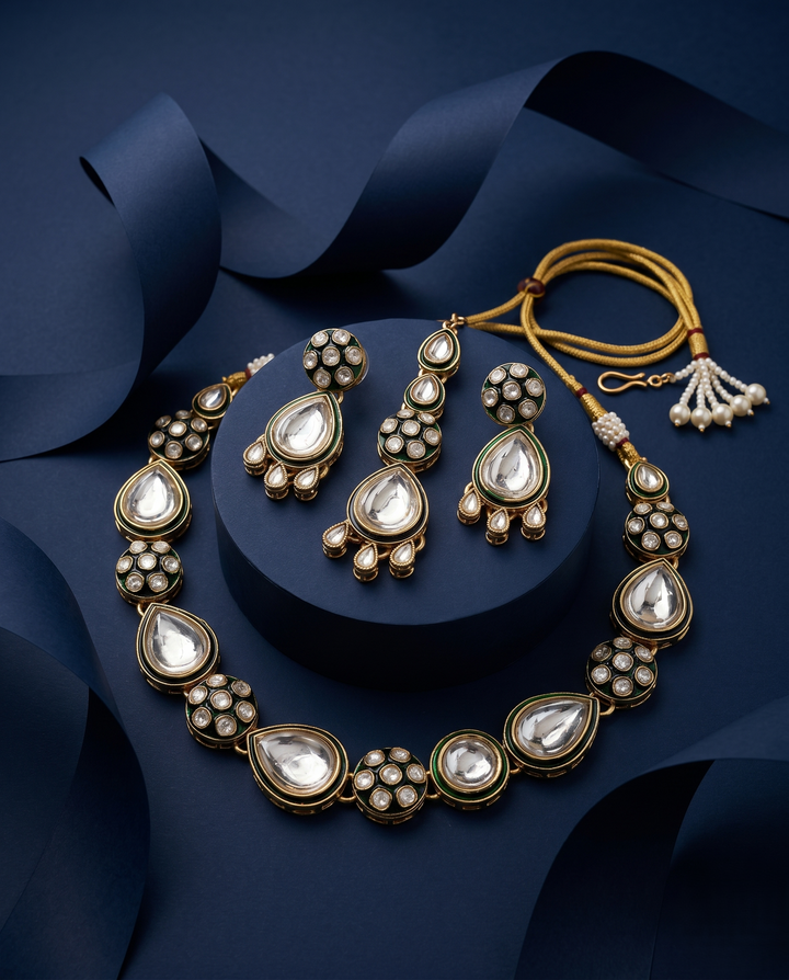 Close up view of polki kundan necklace with pear shaped stones paired with matching earrings in gold finish with blue background 