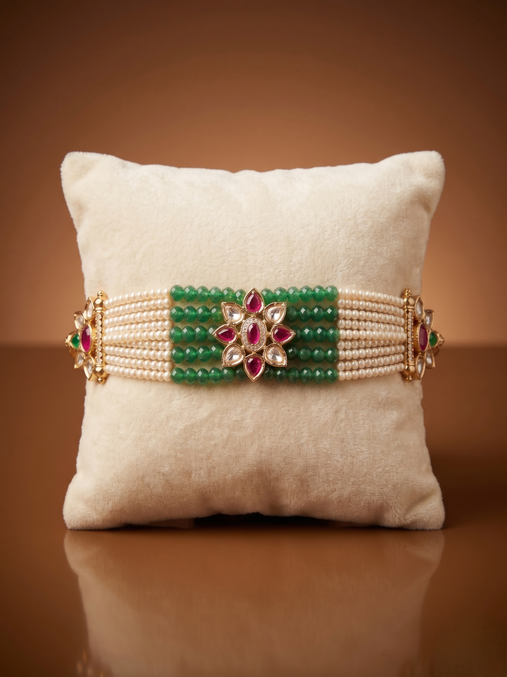 Decorative bracelet with green beads and pink stones on a beige pillow against a brown background