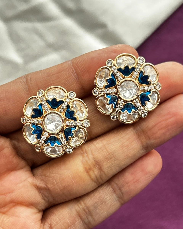 Decorative earrings held in a hand with a blurred background