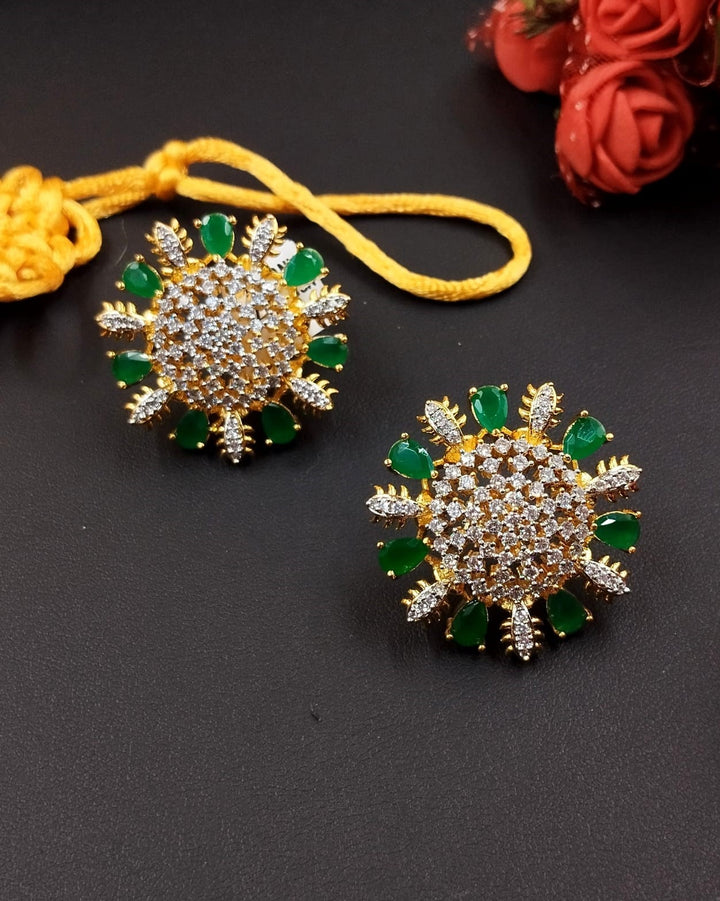 Decorative earrings with green gemstones on a dark surface