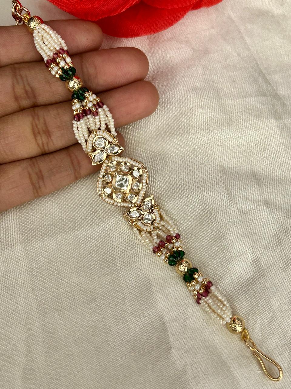 Decorative keychain with beads and gold accents held by a hand on a light fabric background.