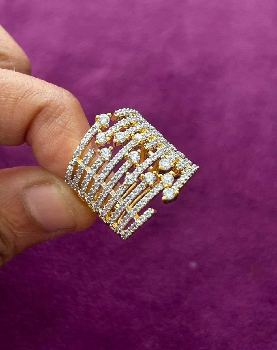 Decorative ring with gold and silver accents held by a finger against a purple background