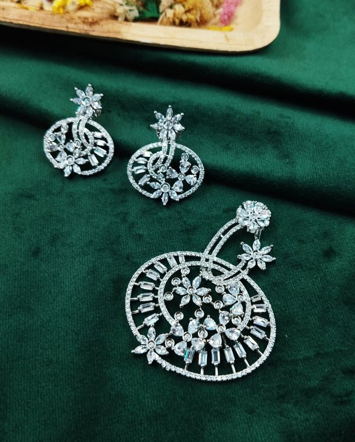 Decorative silver earring on a green fabric background