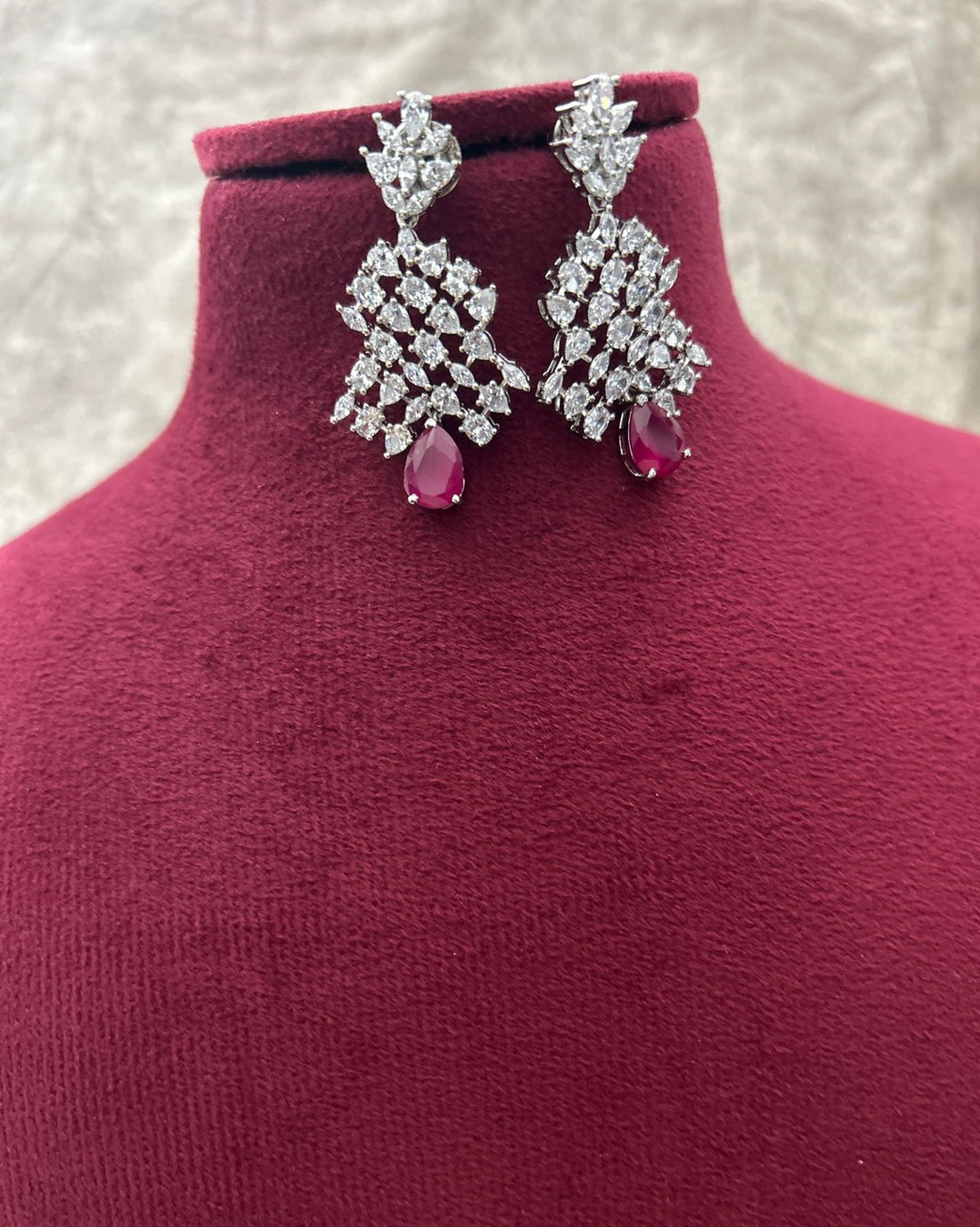 Diamond and ruby earrings on a mannequin bust with a textured background