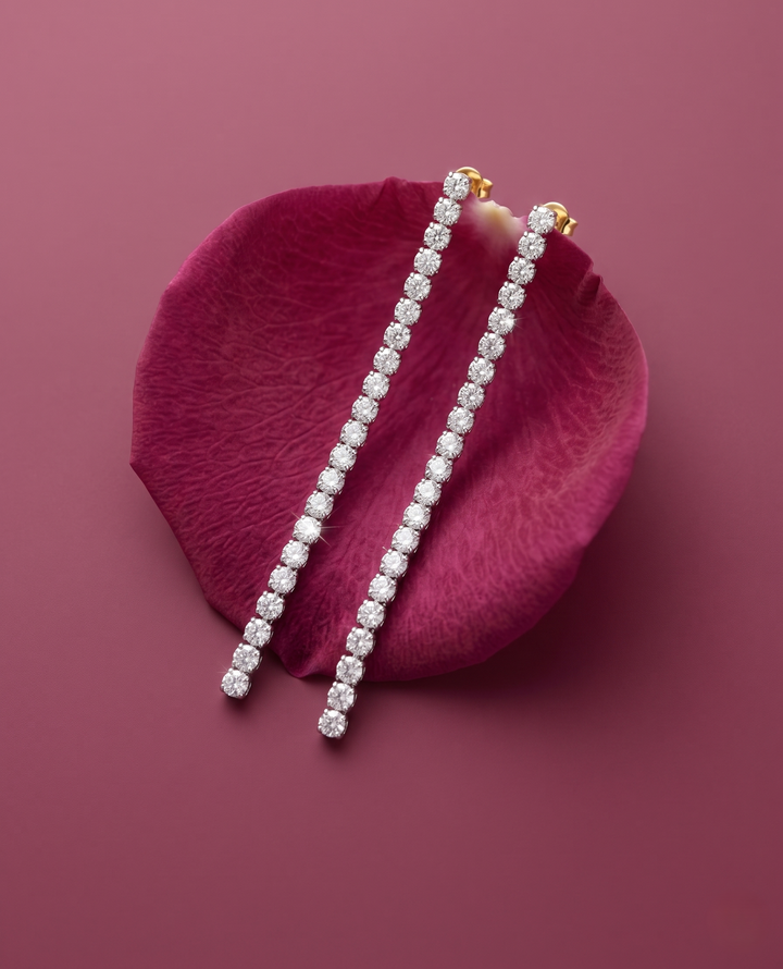 Diamond earrings on a pink petal against a pink background