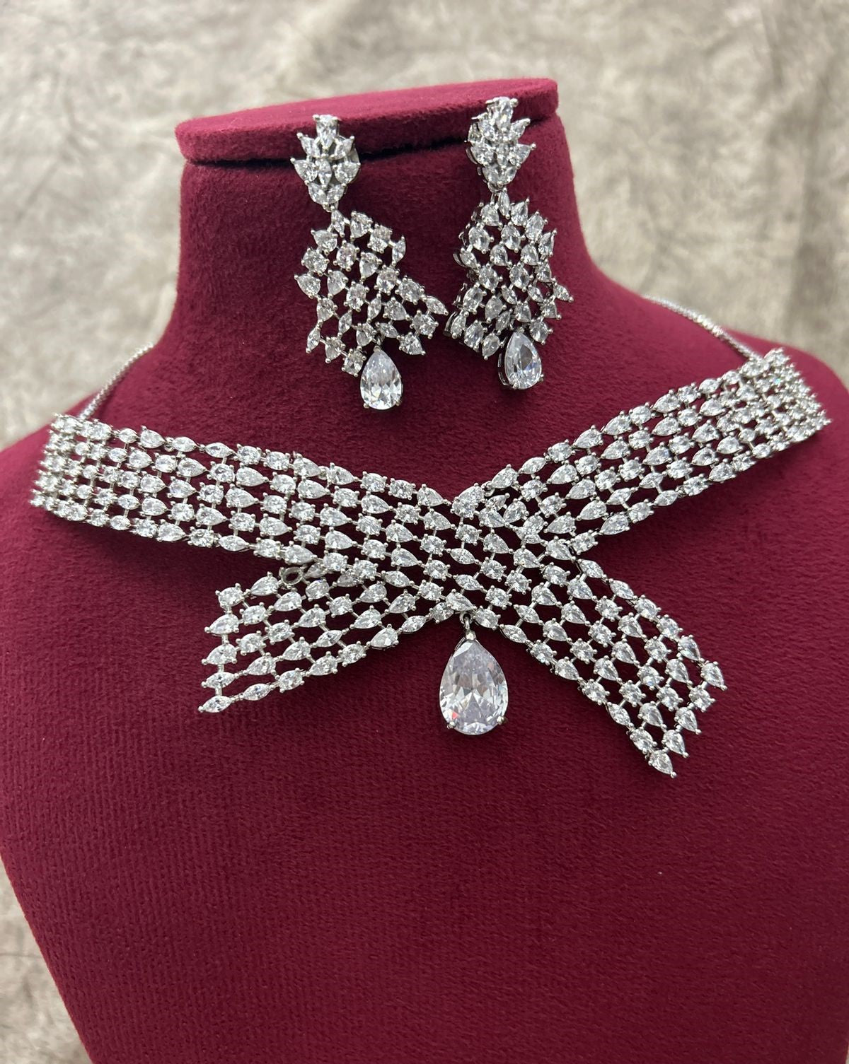 Diamond necklace and earrings set on a mannequin bust with a textured background