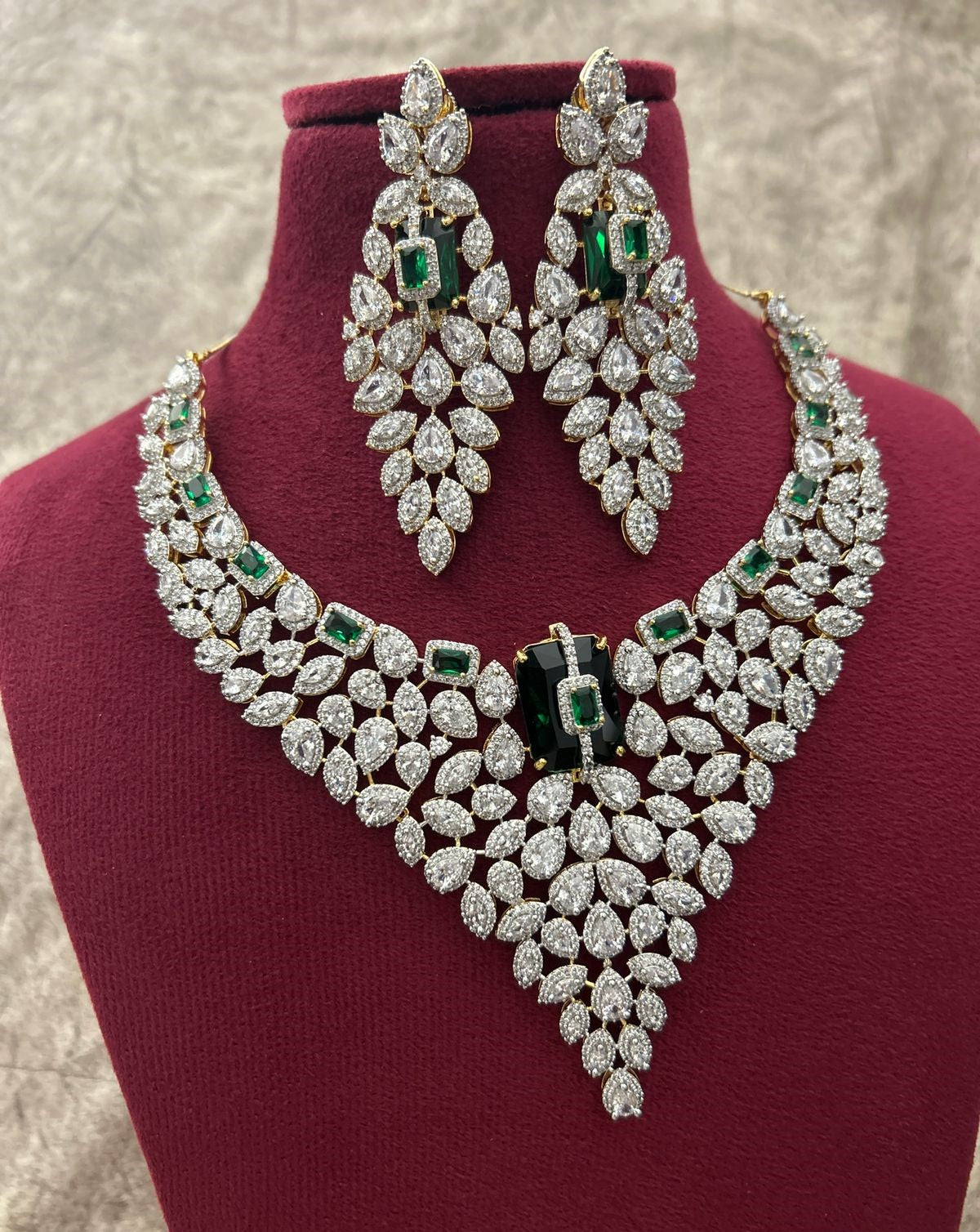 Diamond necklace and earrings set on a red stand with a neutral background