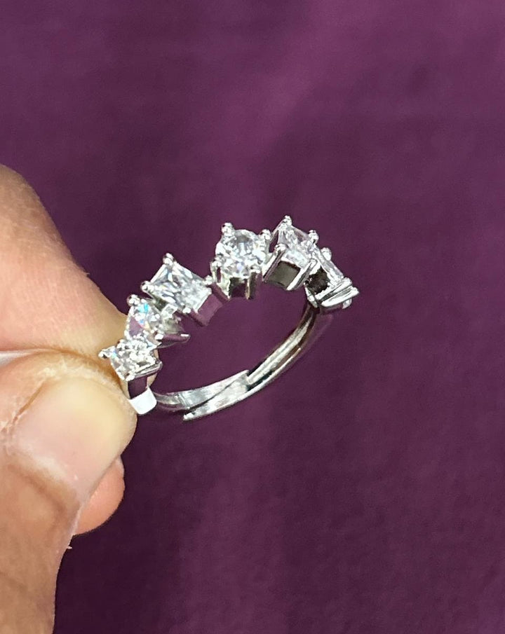 Diamond ring held by a hand against a purple background