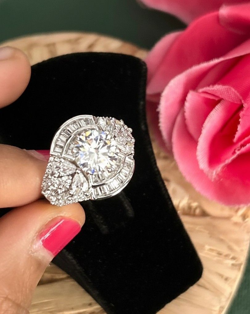 Diamond ring on a black cushion with pink flowers in the background