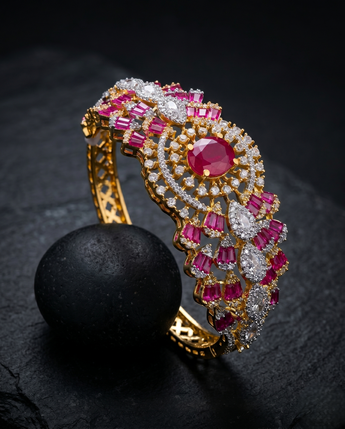 Elaborate gold bracelet with pink and white gemstones on a dark surface