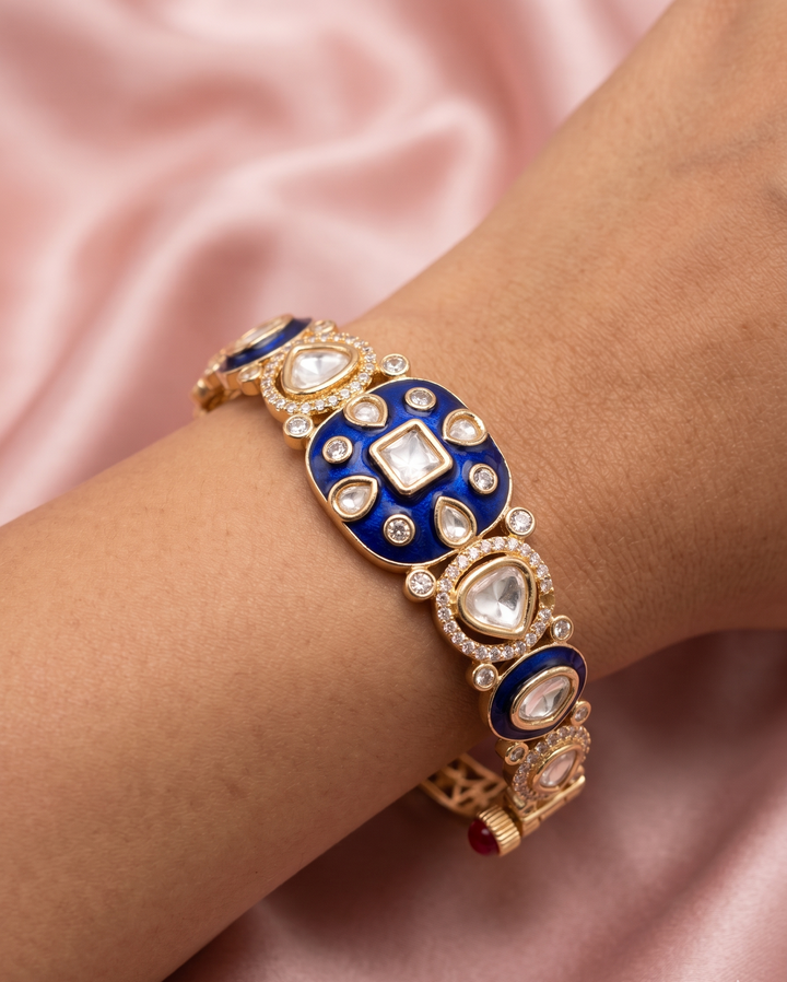 Elegant bracelet with blue and gold design on a wrist against a pink satin background