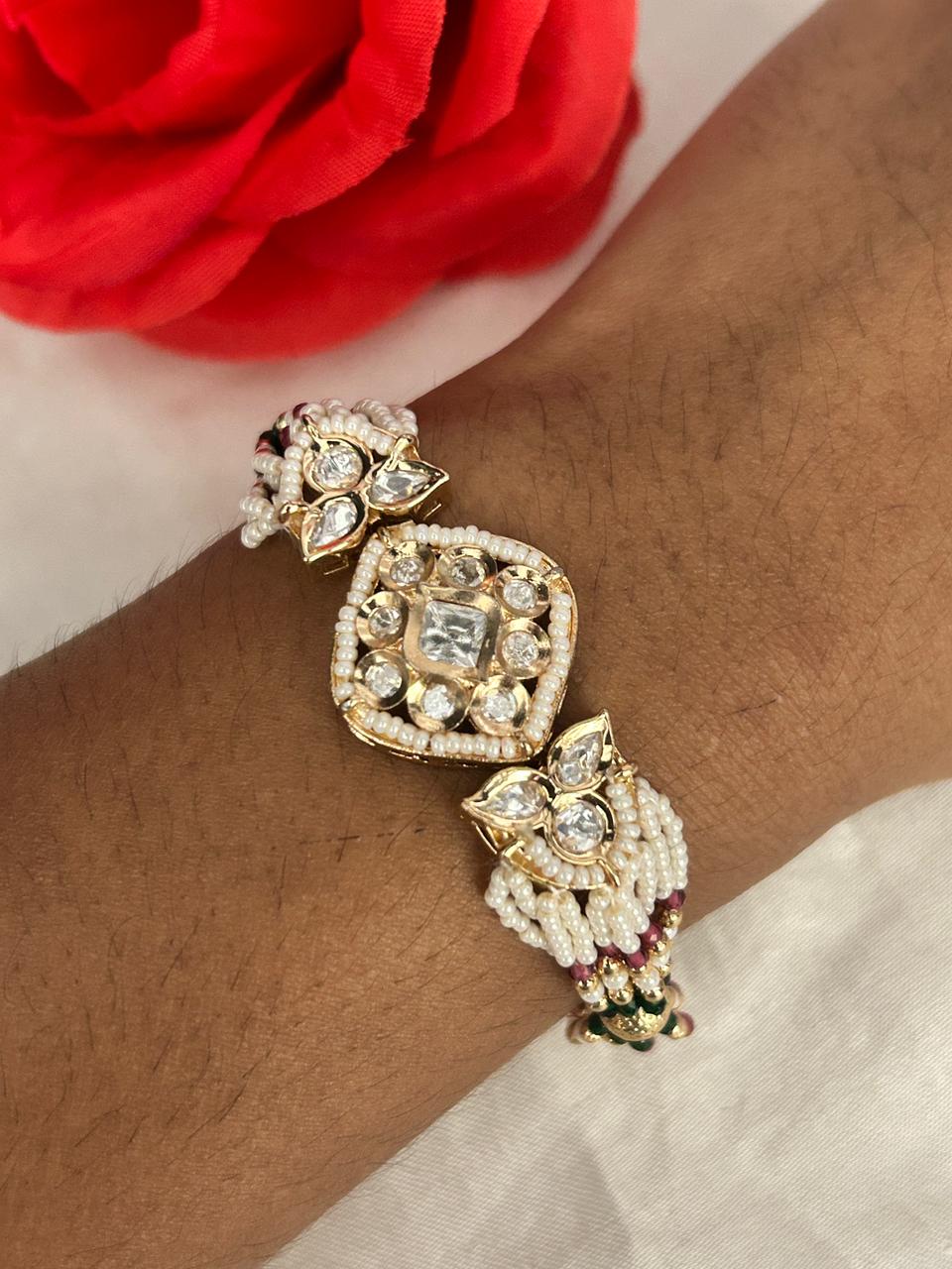 Elegant gold bracelet with gemstones on a wrist, red flower in the background