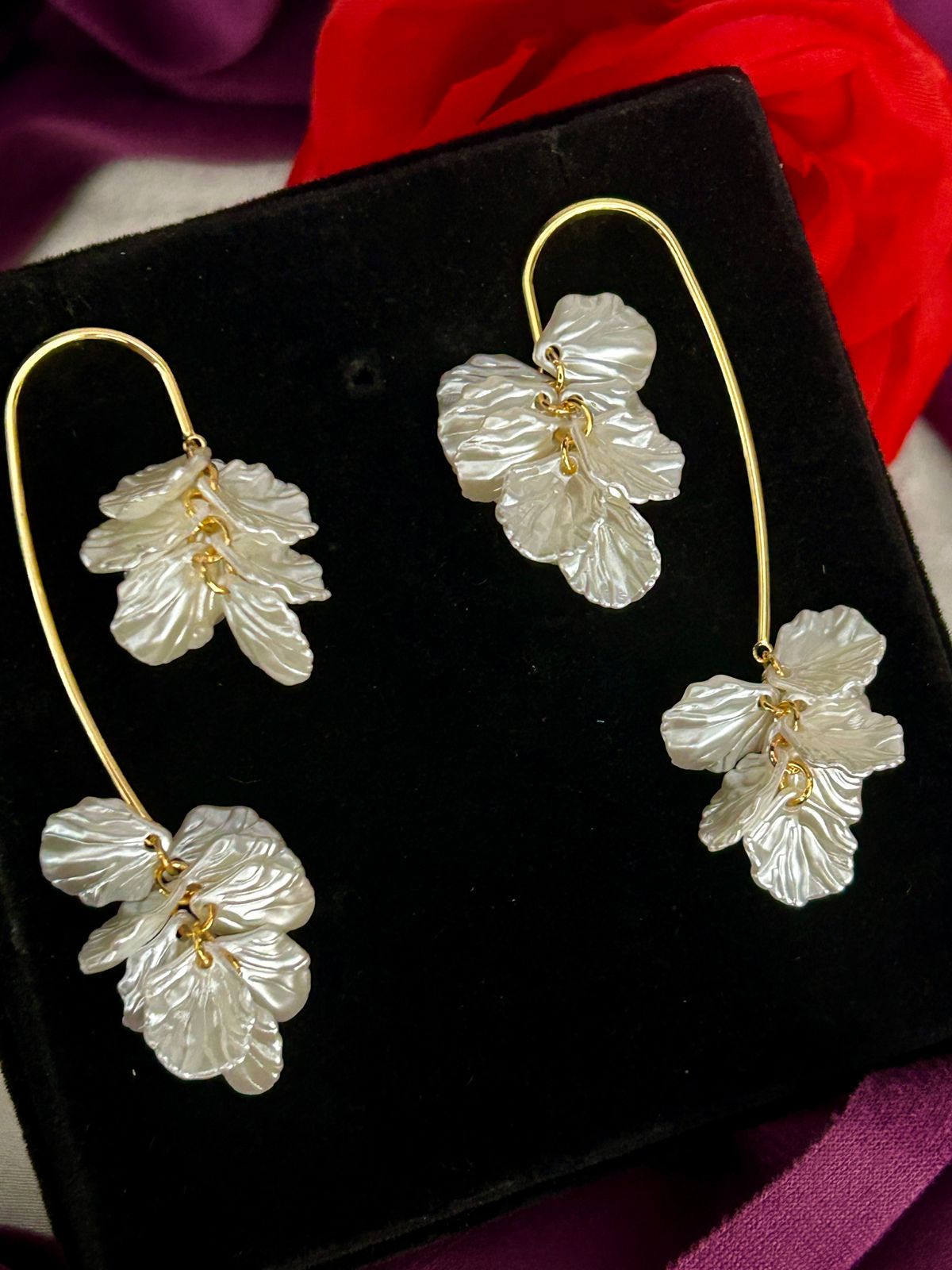 Floral earrings on a black display box with a red fabric background