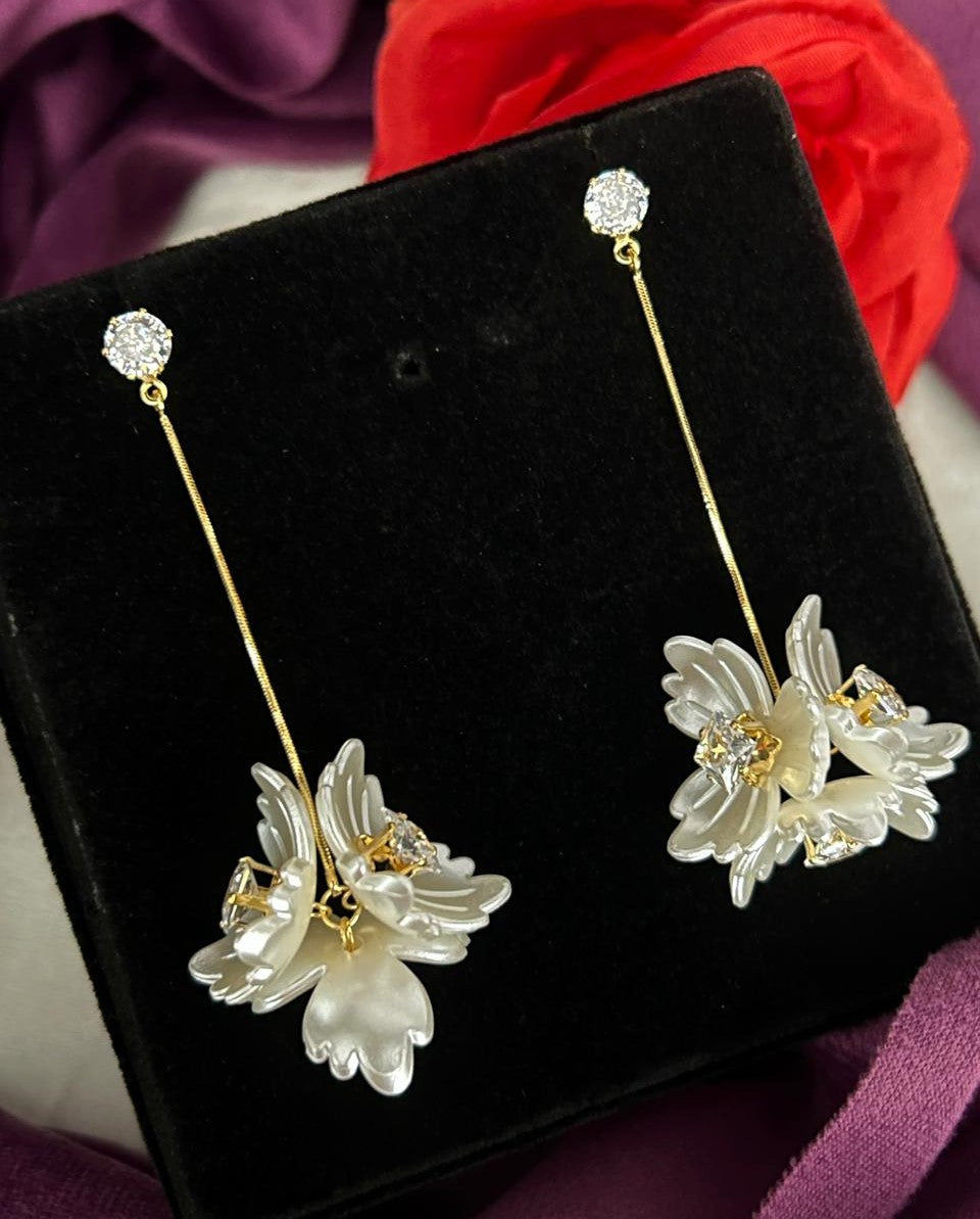 Floral earrings on a black stand with a red flower in the background