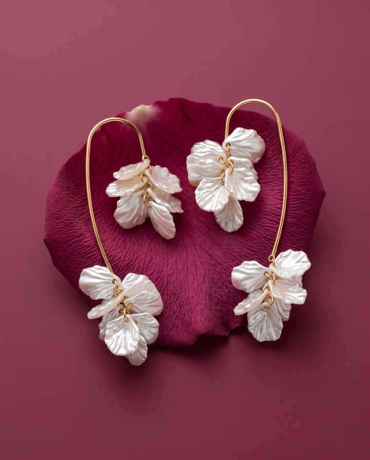 Floral earrings on a pink petal against a matching pink background