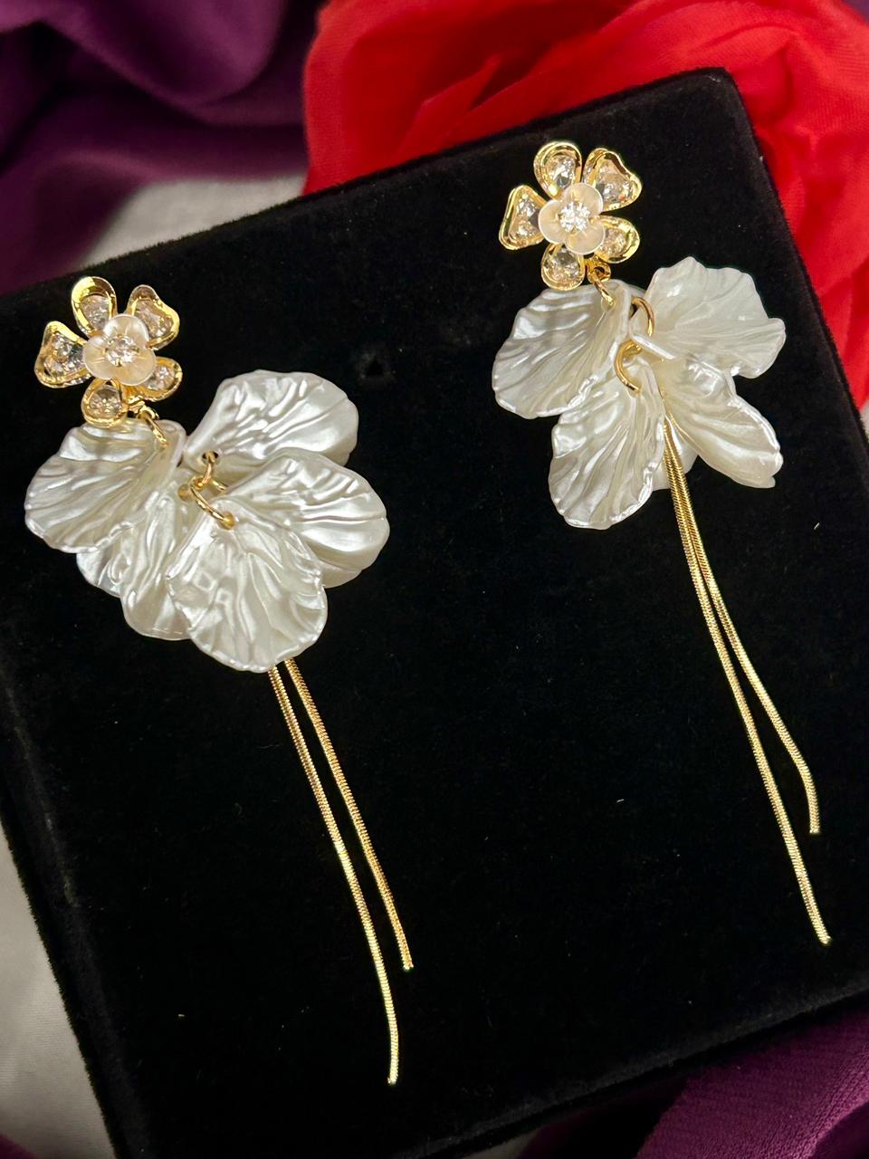 Floral earrings with gold and pearl details on a black background