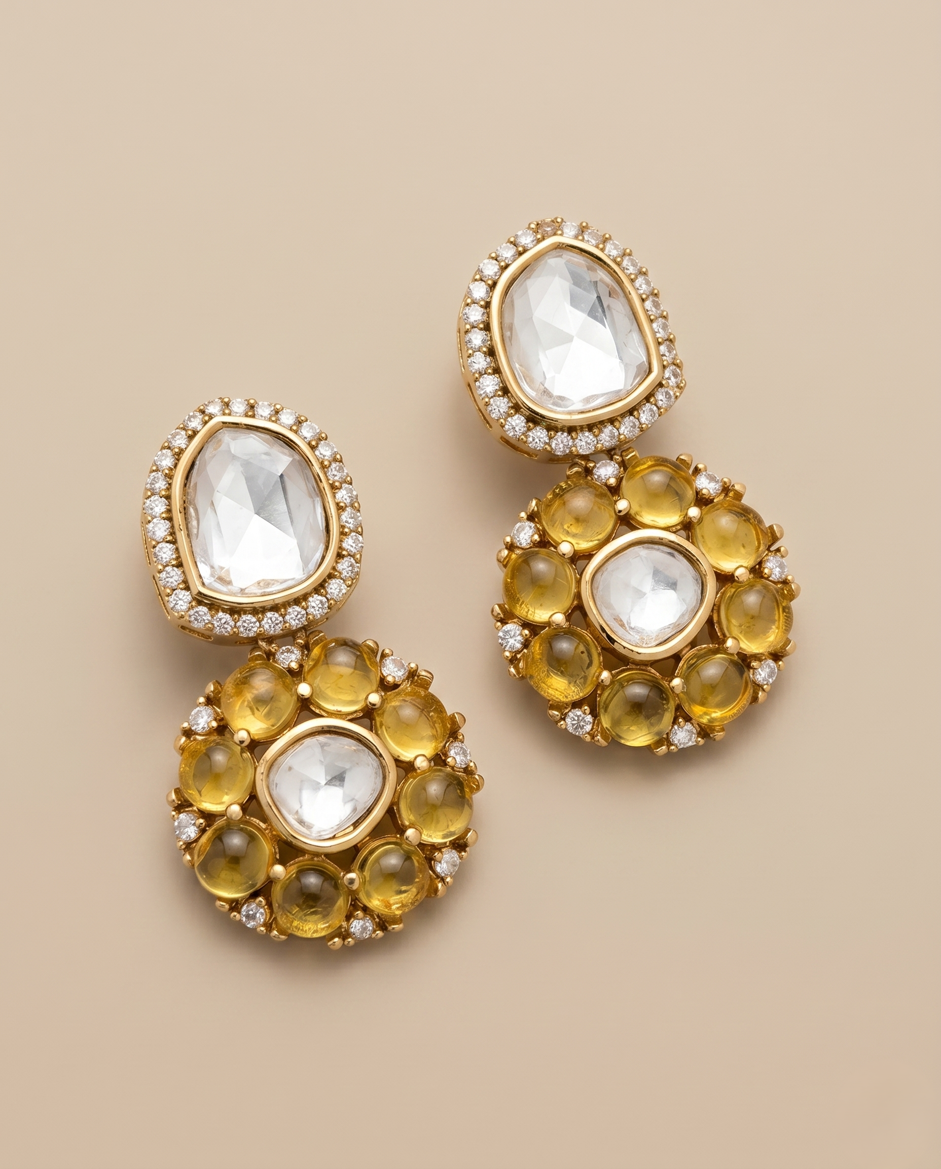 Gold earrings with clear and yellow gemstones on a beige background