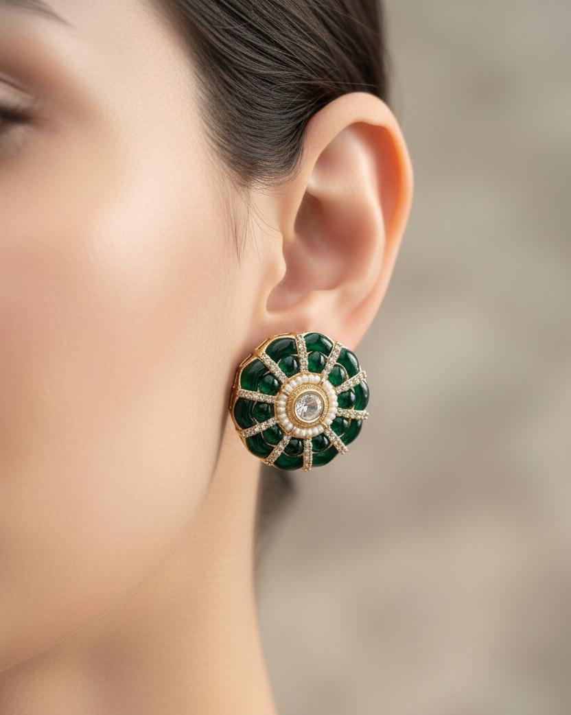 Close-up of a woman's ear wearing a green emerald earring with a blurred background