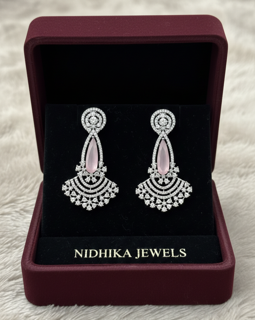 Pair of earrings in a Nidhika Jewels box on a textured surface