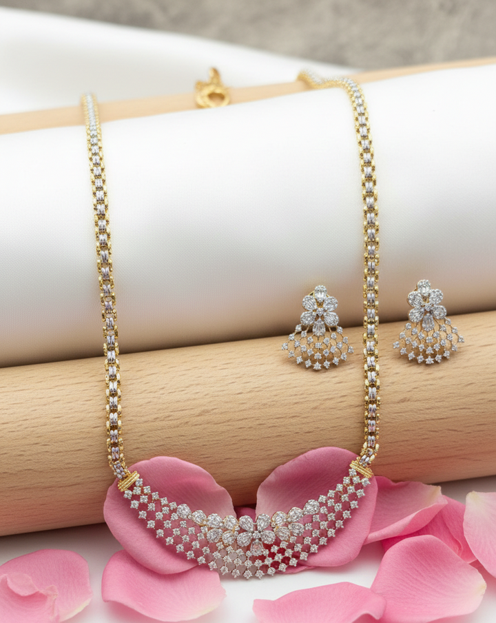Gold necklace with diamond accents and matching earrings on pink petals