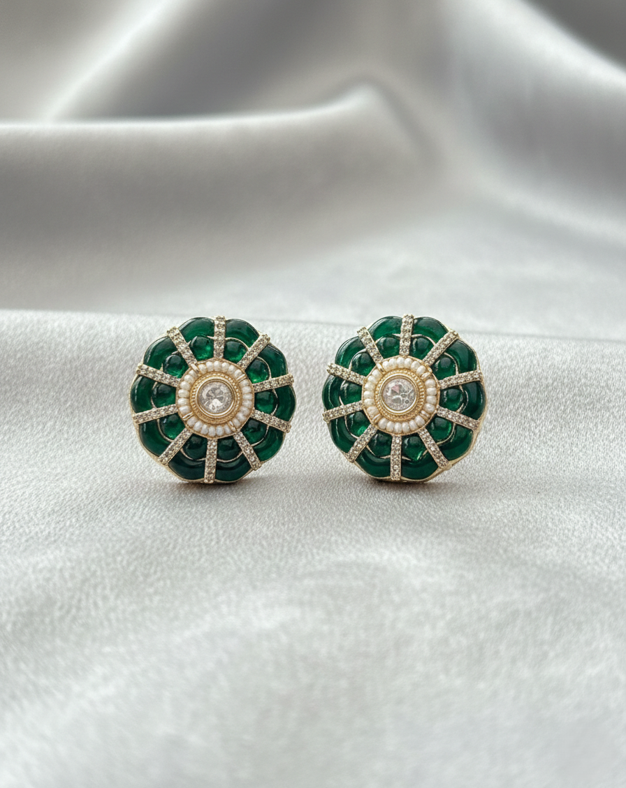 Pair of green earrings with gold accents on a white fabric background