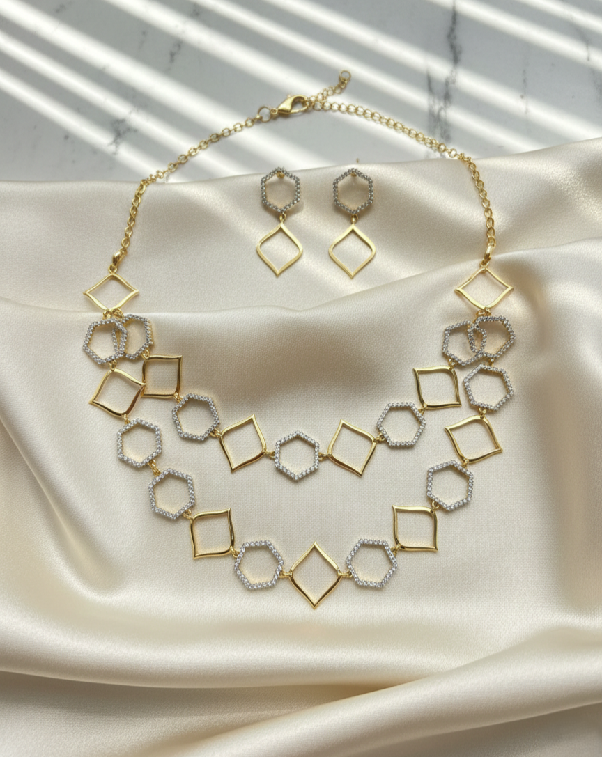 Gold and silver geometric necklace and earrings on a satin surface