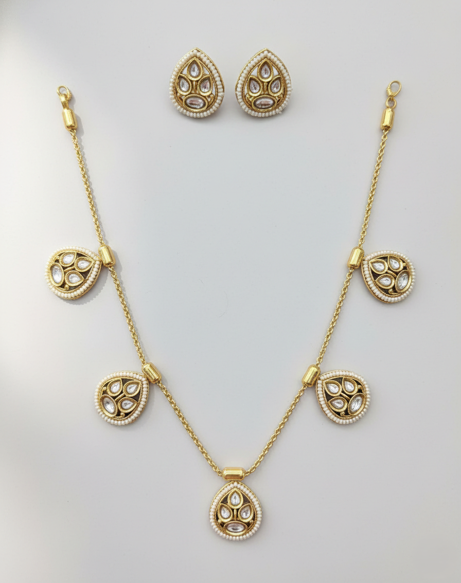 Gold necklace and earrings set on a light gray background