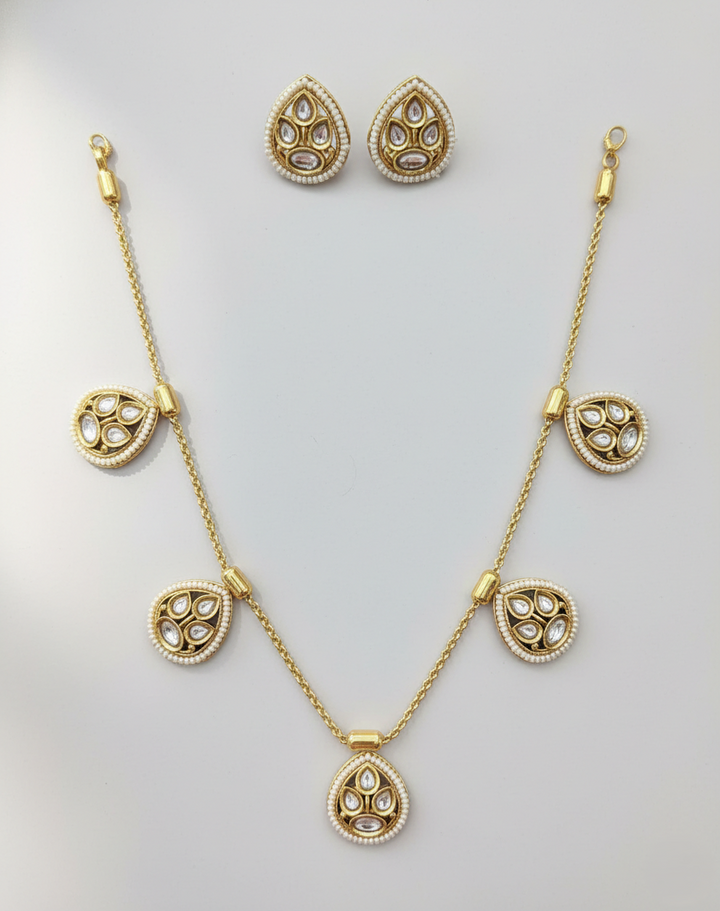 Gold necklace and earrings set on a light gray background