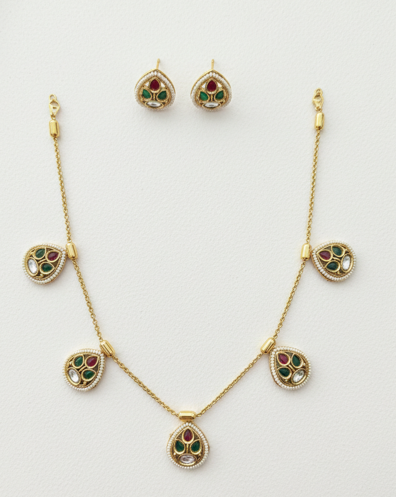 Gold necklace and earrings with gemstone accents on a white background
