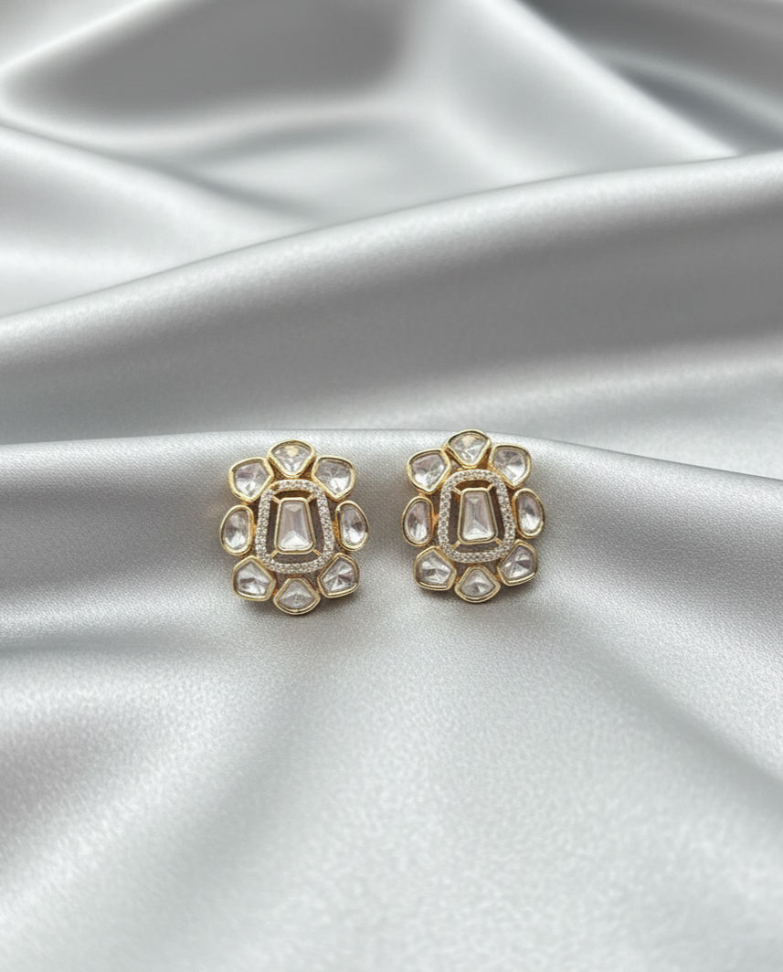 Gold earrings with gemstones on a silver satin background