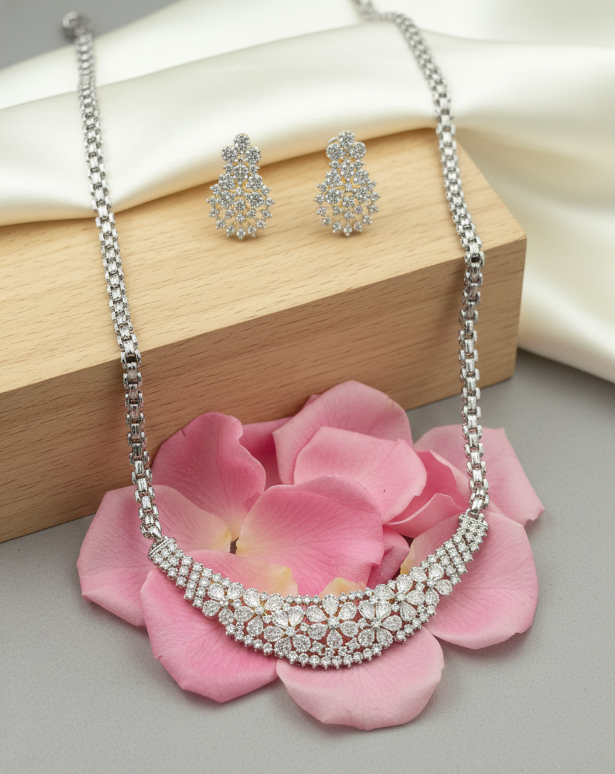 Silver necklace and earrings on pink flowers with a neutral background