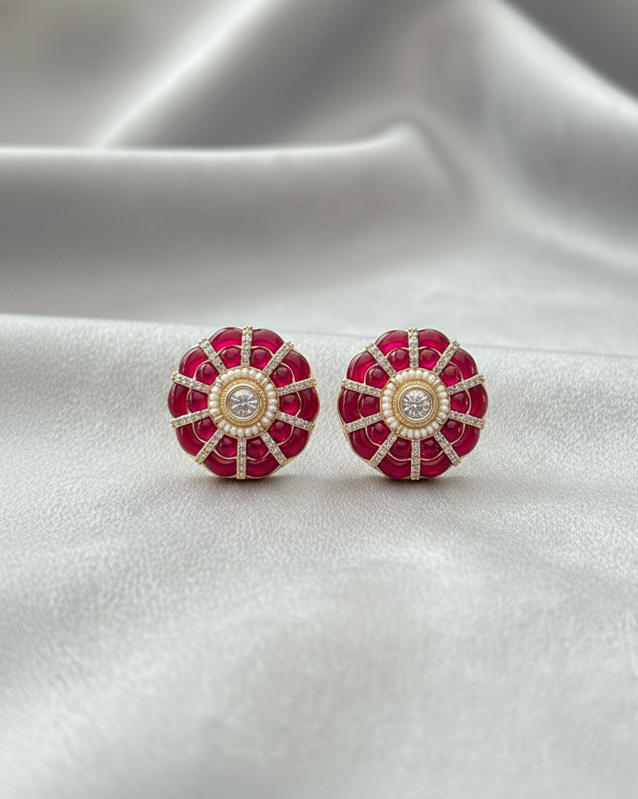 Red and gold earrings on a white fabric background