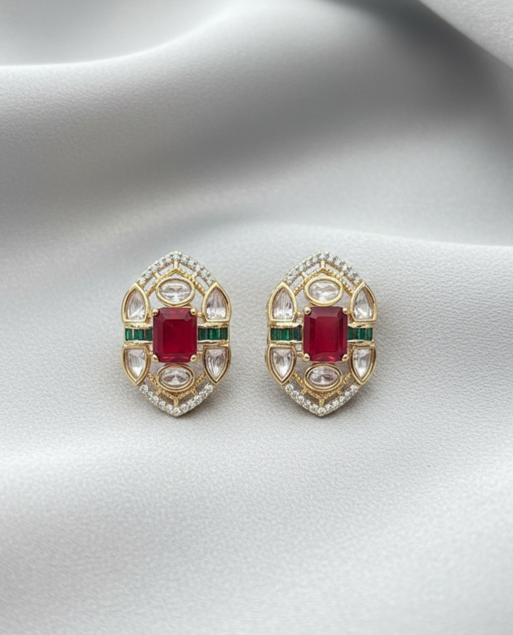 Pair of gold earrings with red gemstones on a white background